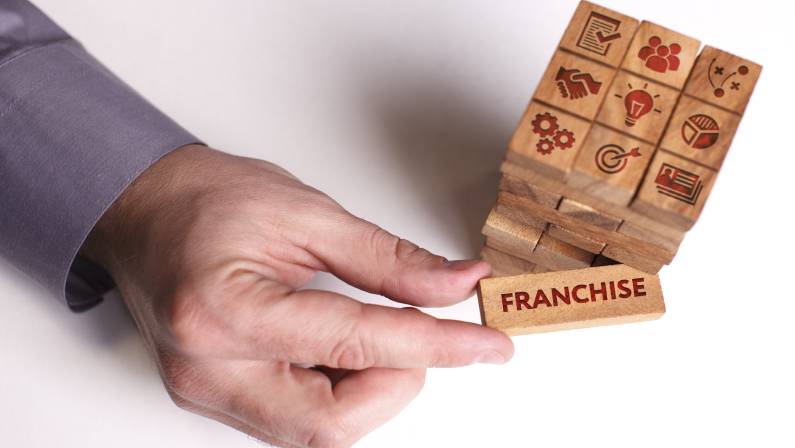 Young businessman shows the word: Franchise